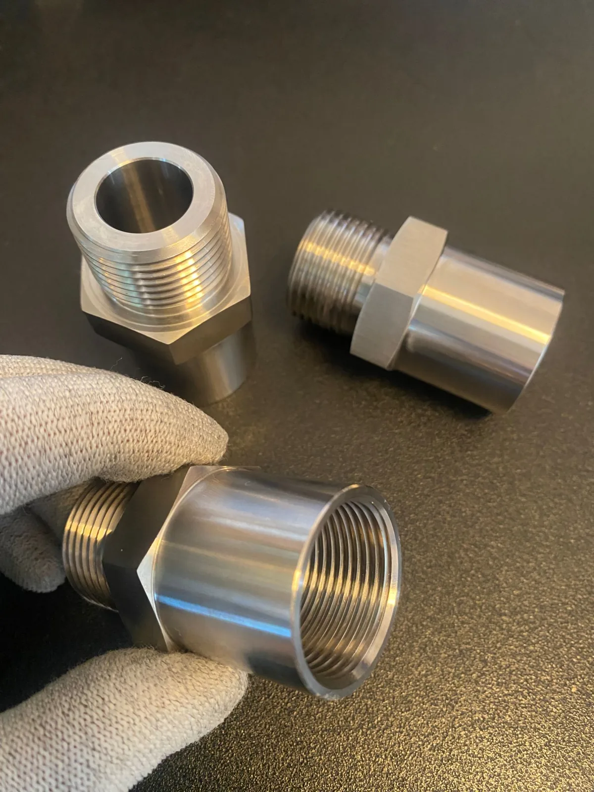 Three M27×2 male to M27×1.75 female thread adapters in 316 stainless, hex flats, 16 mm through bore, machined by EKINSUN