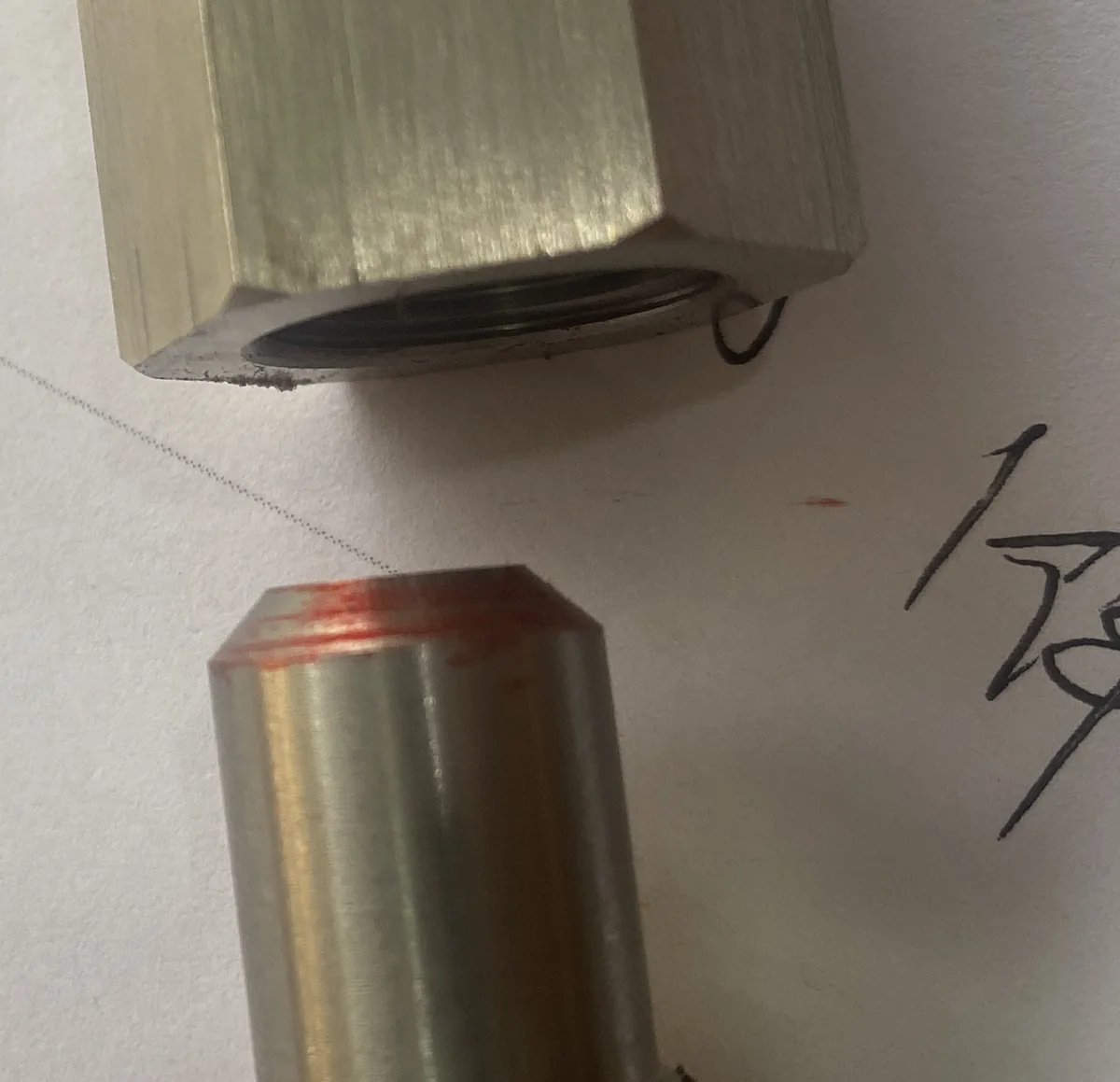 Two-piece custom 316 stainless sealed adapter separated on the bench, elastomer seal captured in the machined counterbore of the female half, red marking compound transferred onto the lead-in chamfer of the male sealing land — EKINSUN