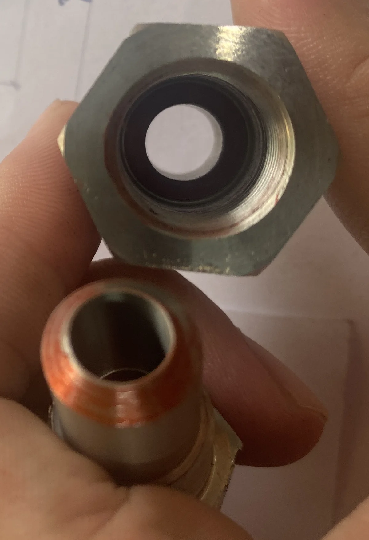 End view of the female half showing the black elastomer seal seated in the machined counterbore behind the internal thread, and a full unbroken red witness ring around the male half's sealing land — EKINSUN
