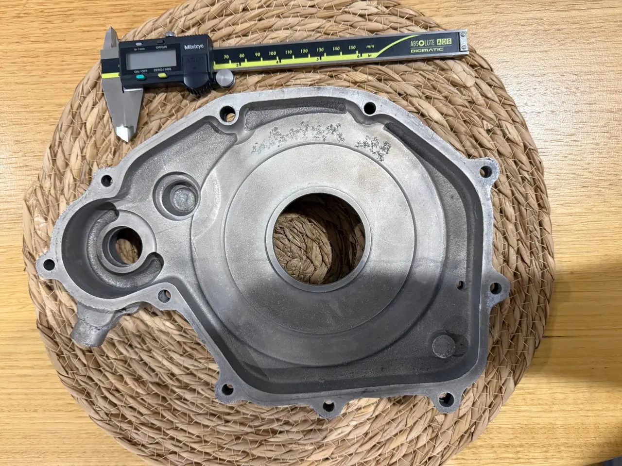 The opposite face of the same 125cc clutch cover casting, again photographed straight down with a caliper alongside — a top-down frame cannot show how deep the recess runs
