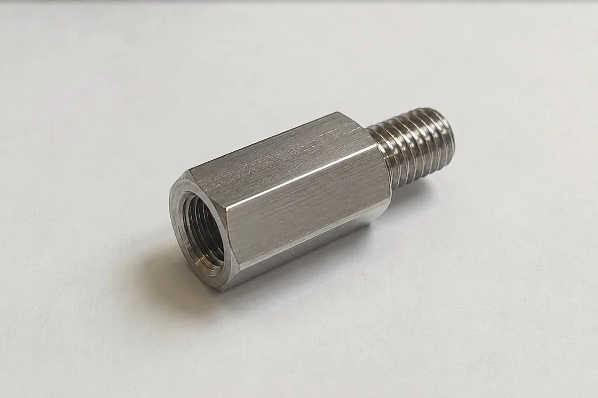 Real custom male-female reducing thread adapter machined from 304 stainless, with an internal M24×2 thread inside the hex end and a smaller external M20×1.5 male thread on the other end