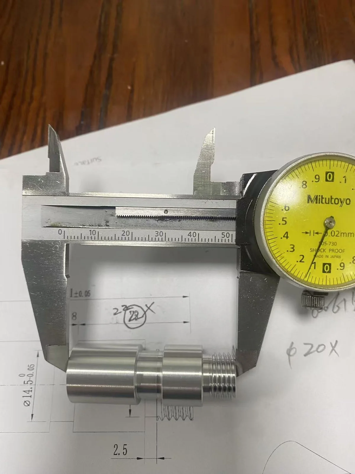 Dial caliper measuring the Ø14.5 toleranced diameter on the multi-thread stud against the technical drawing