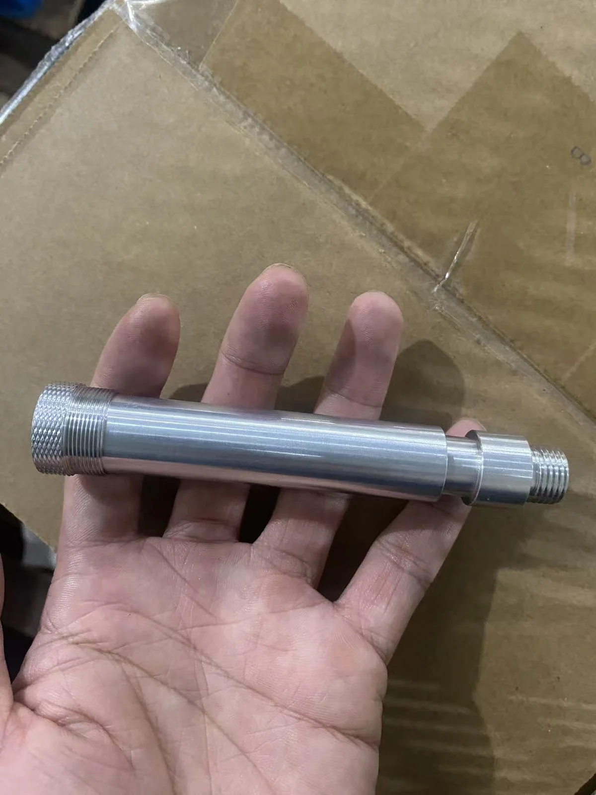Finished stainless steel knurled multi-thread stud held in hand, showing the 9/16-18 UNF thread, knurled grip and 13/16-28 UN thread section