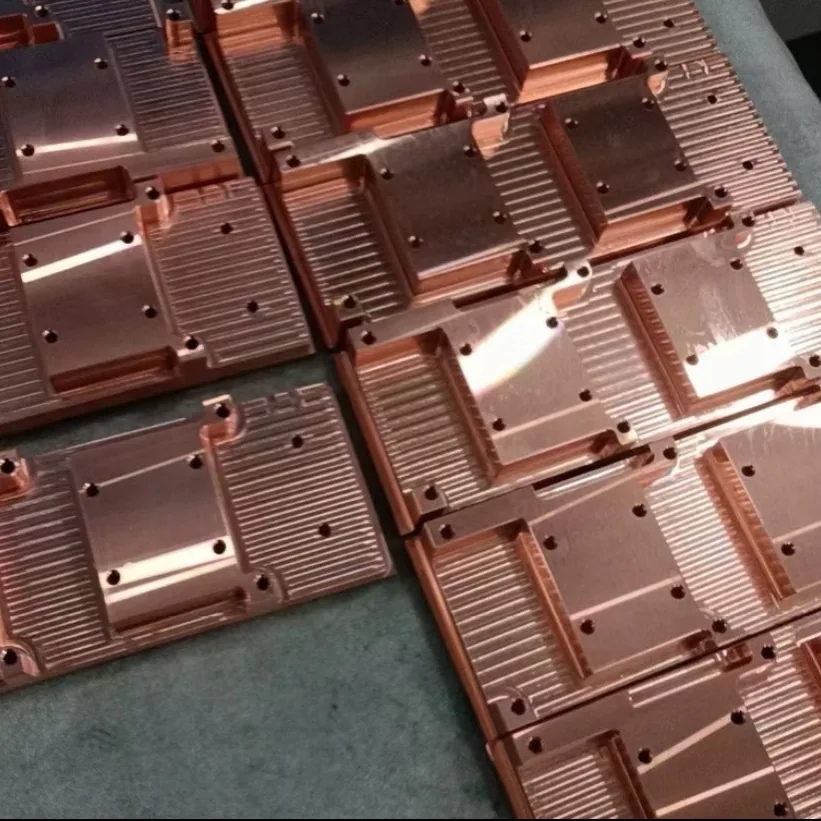 Rows of machined copper plates, each with a grooved fin field, a flat raised pad and threaded mounting holes