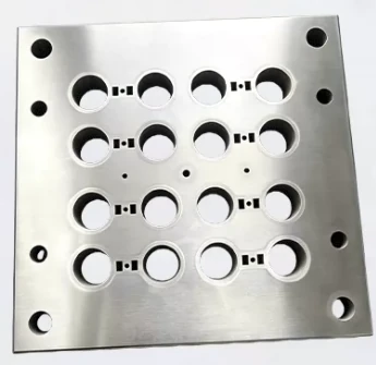 Ground steel plate with sixteen counterbored openings, each flanked by small sharp-cornered rectangular slots