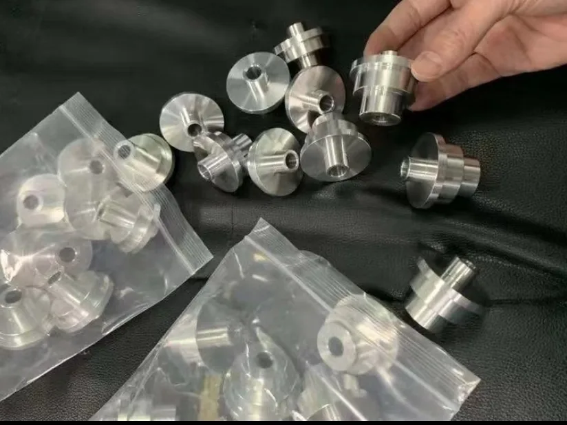 Stepped flanged bushings on a dark surface, some loose and some in zip bags