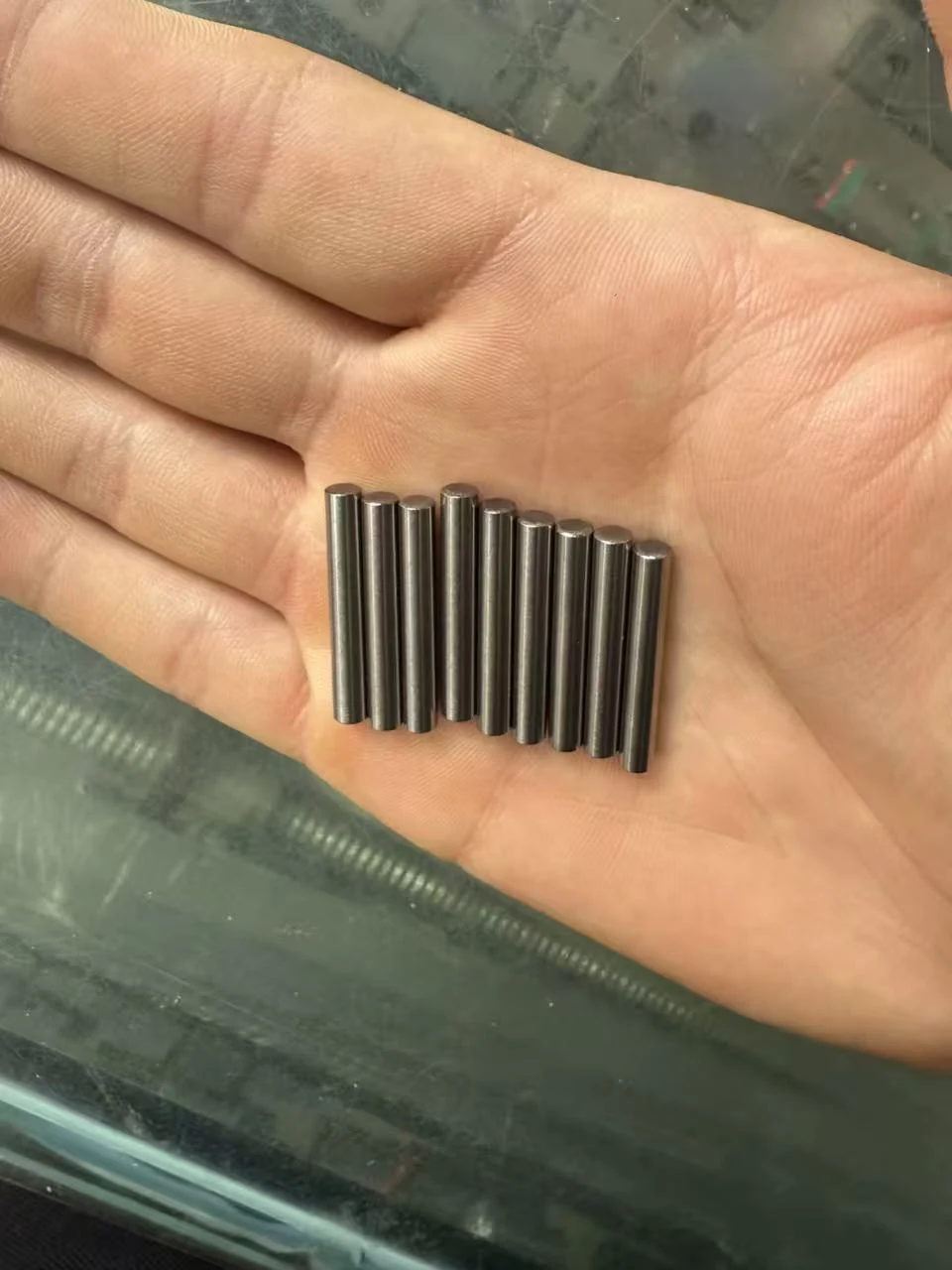 Petites goupilles cylindriques trempées rectifiées tenues dans une main — pions de centrage de précision usinés par EKINSUN