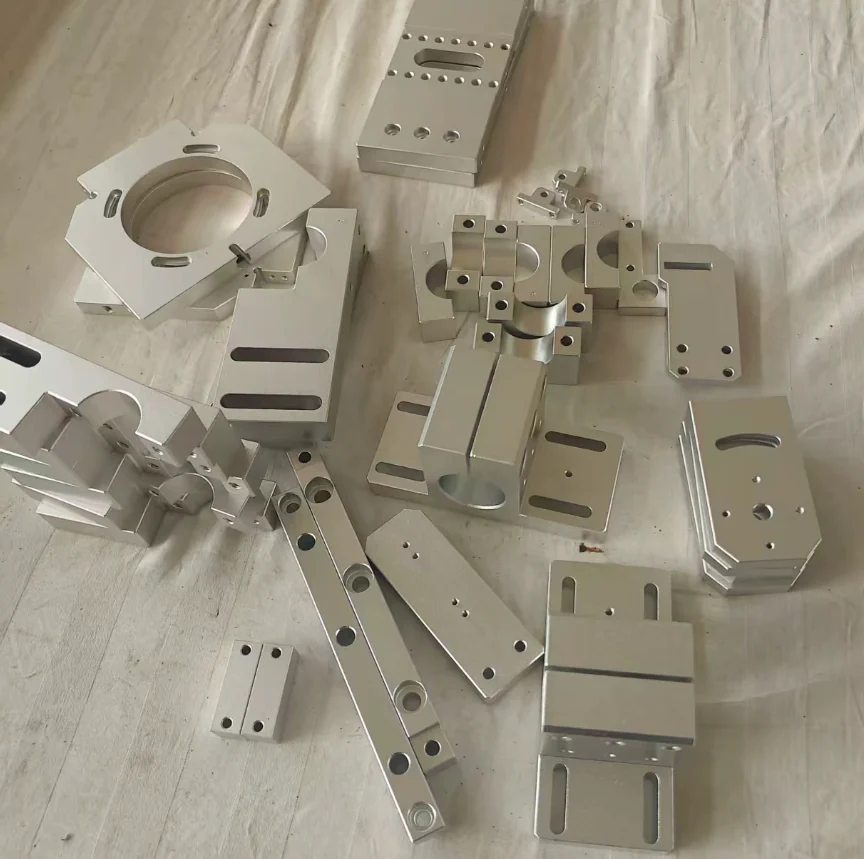 Machined aluminium split shaft clamps, bearing support blocks, motor mounts, slotted adjustment brackets and a large bored flange plate laid out together