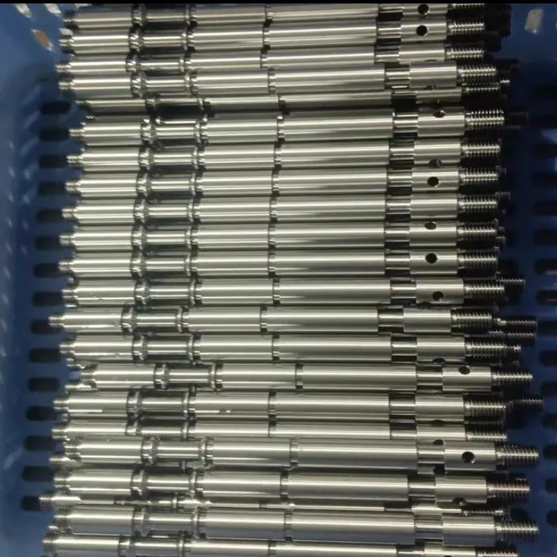 Crate of turned stems laid side by side, each with grooves, a cross hole and a threaded end