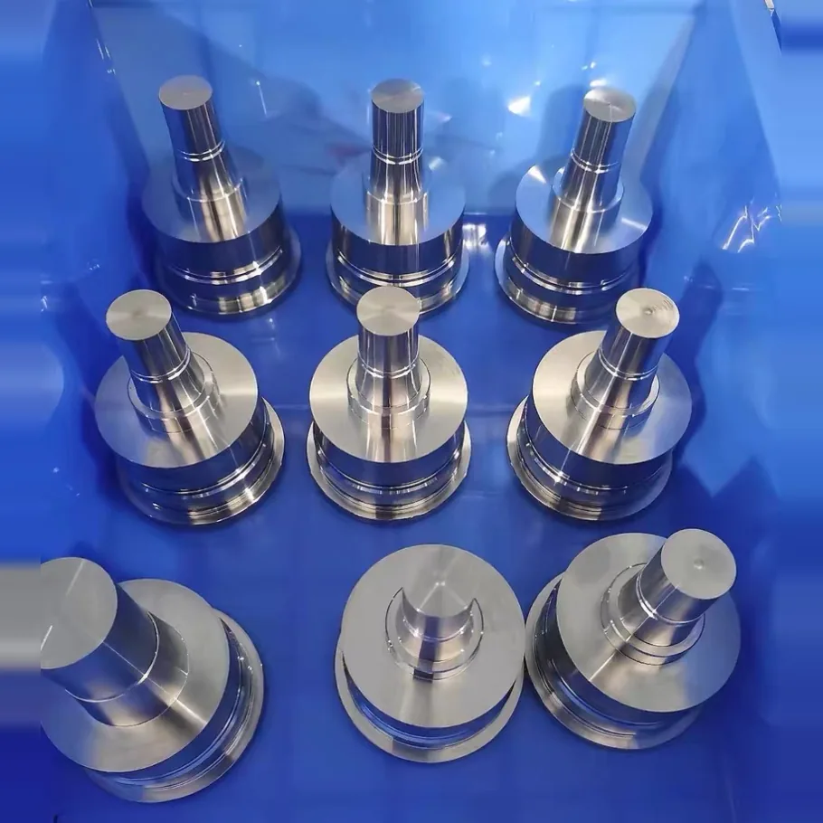 Nine turned stepped parts with a wide flanged base standing in a blue crate