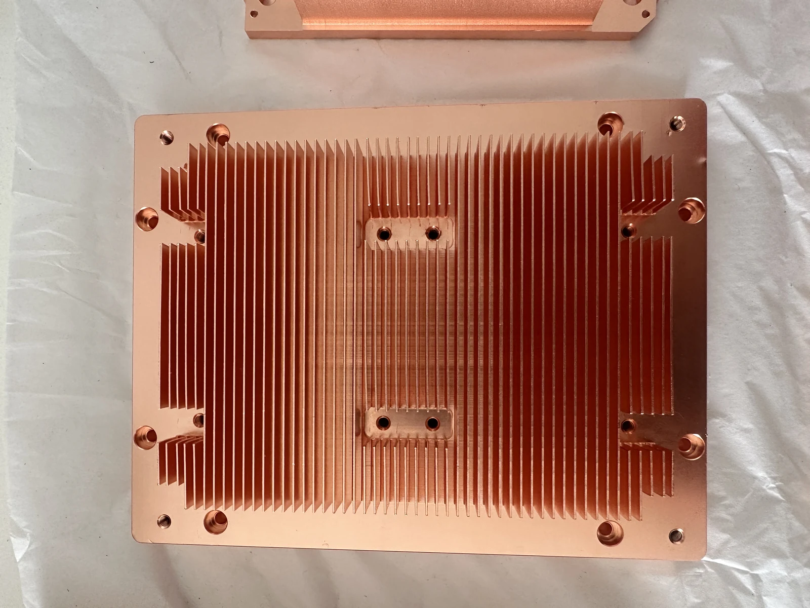 Large copper skived fin heat sink with fin fields at several different heights, two machined flat pads inside the fin field and counterbored mounting holes
