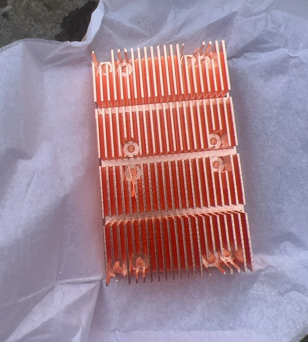 Copper skived fin heat sink with the fin field broken into four segments and clearance notches cut so mounting screws pass through