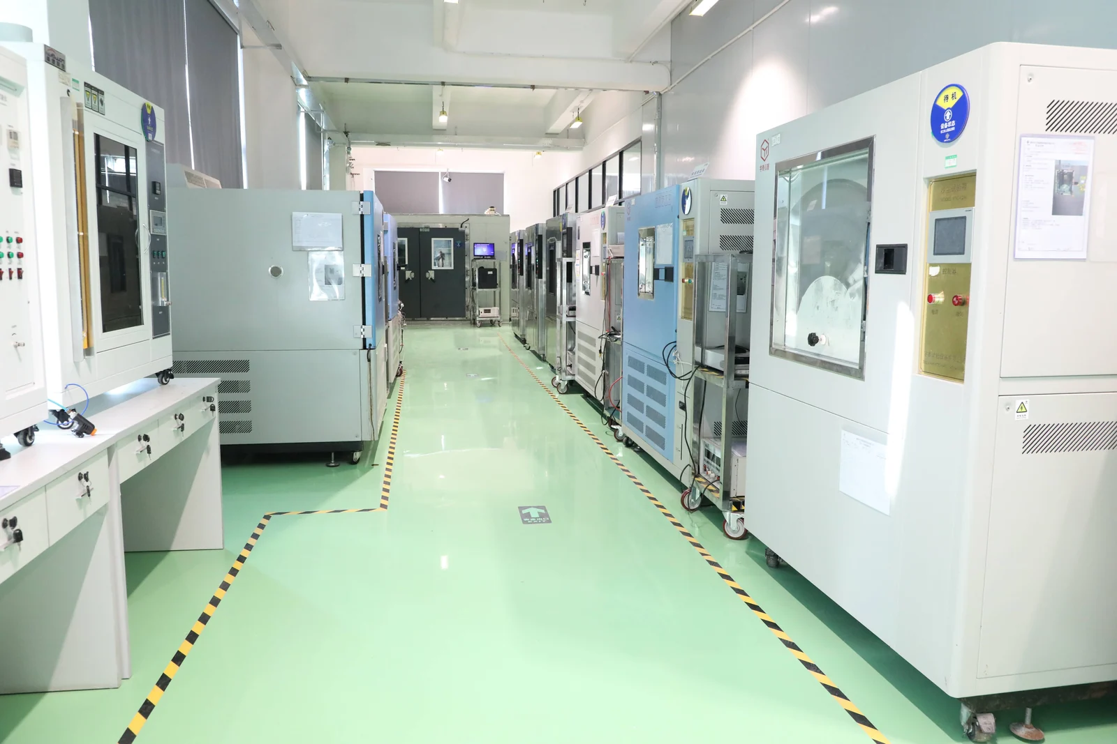Environmental testing laboratory with a row of temperature and humidity test chambers used for conditioning and accelerated ageing