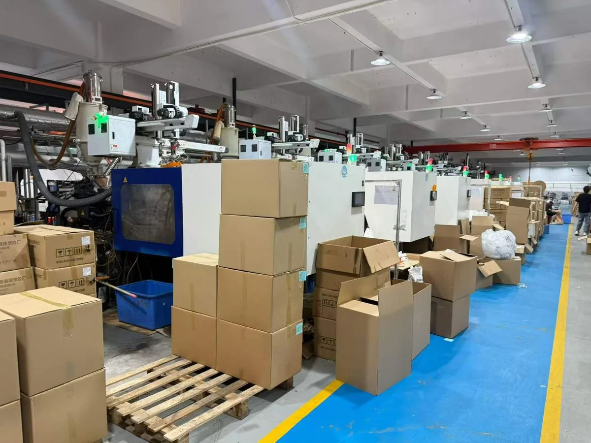 Injection molding shop floor at a partner facility with hopper dryers, takeout robots and cartons of finished parts