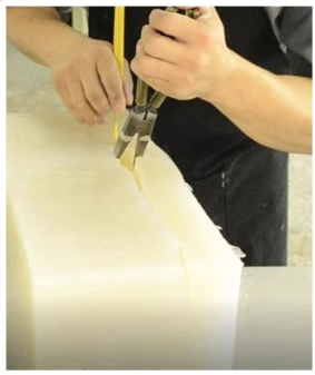 Technician cutting a cured silicone mold open along the parting line to remove the master — vacuum casting