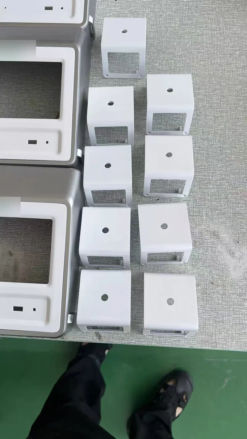 White cast plastic mounting brackets alongside larger cast panel bezels on a workbench