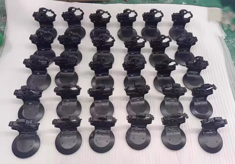 Rows of complex black cast plastic bracket assemblies with fine detail and disc bases