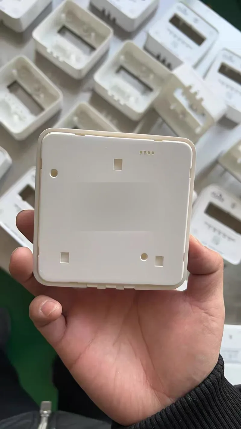 Rear face of a cast plastic housing showing snap-fit slots, screw bosses and locating features