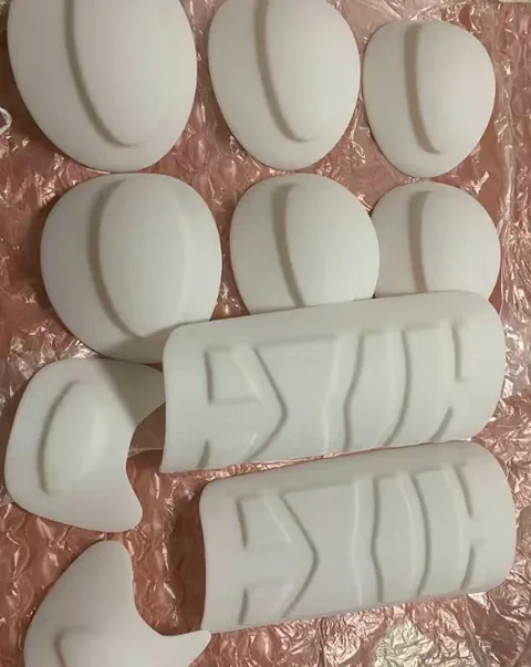 Unpainted white cast polyurethane parts including domed shells and grained grip covers before finishing