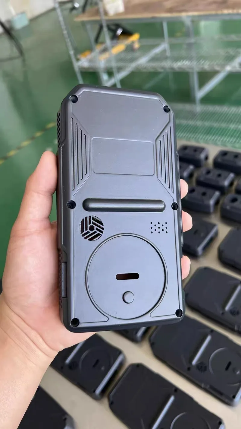Assembled two-tone cast plastic handheld device enclosure with vents, grille and battery cover